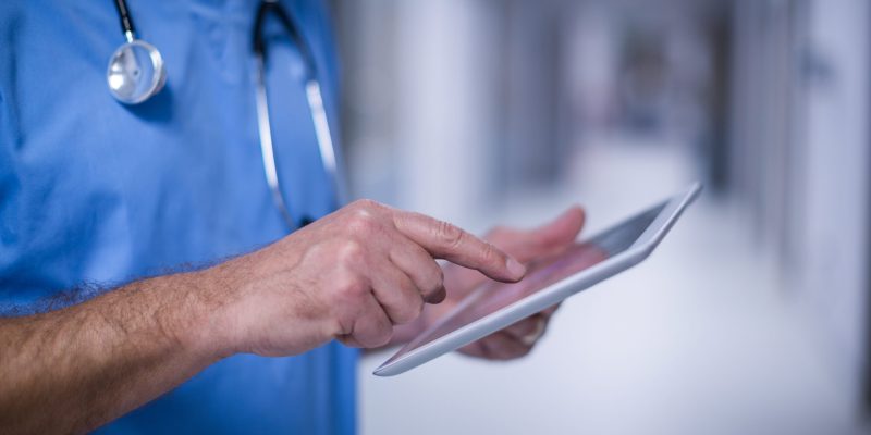 Mid section of male surgeon using digital tablet in operation room at hospital