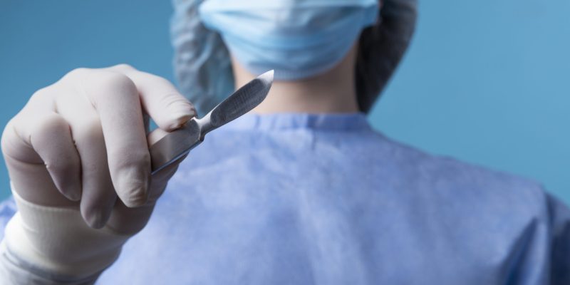 medica-segurando-bisturi-medico-metalico
